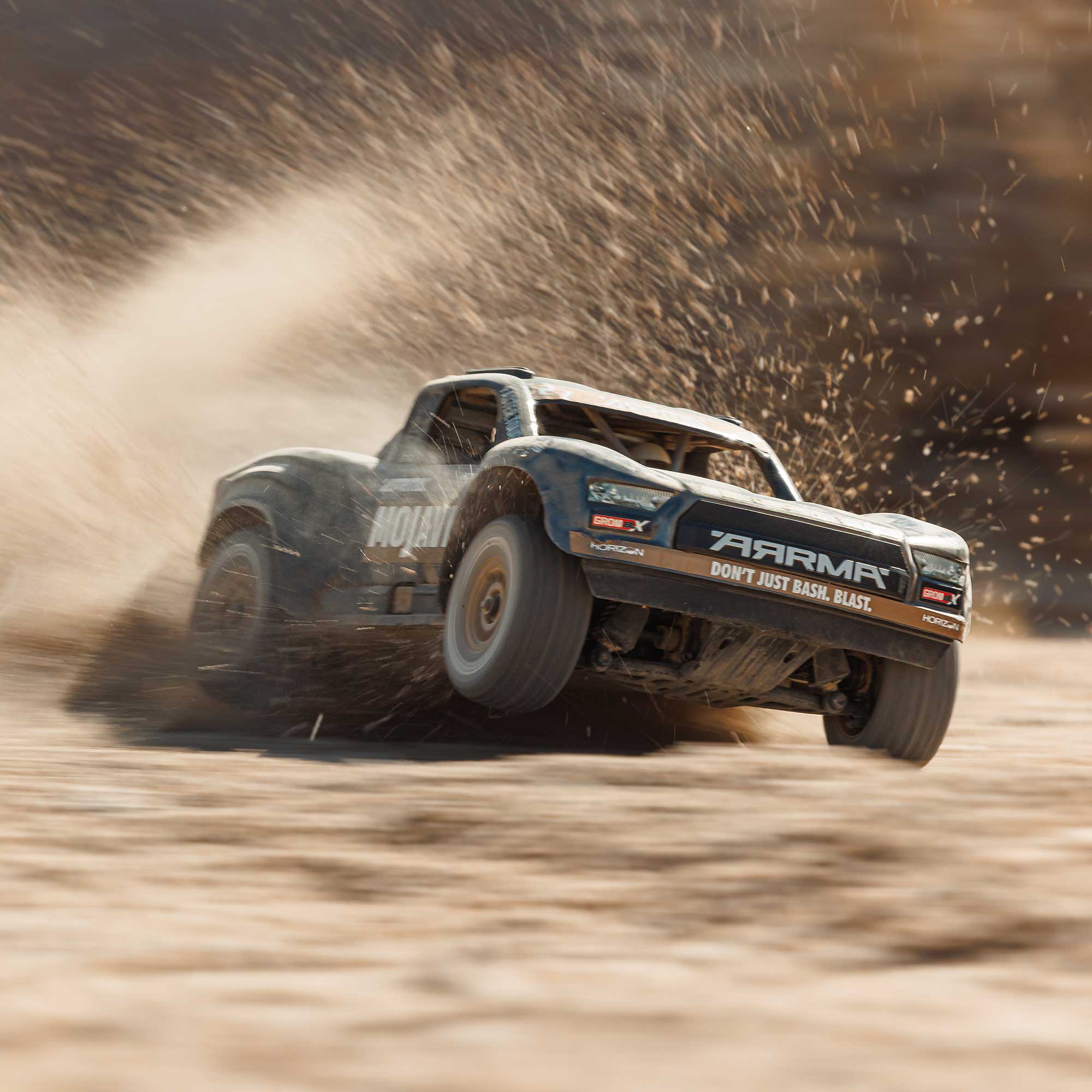 ARRMA manufacturer action photograph showing the black Mojave GROM 223S turning on dirt